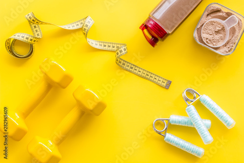 Nutrition for workout with protein cocktail powder and bars on yellow background top view