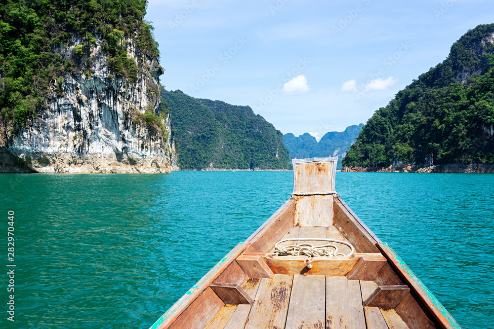 Rock cliff on limestone mountain and wooden boat in lake