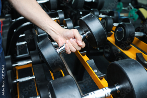 A man are choosing dumbbells for exercise in the gym,Selective focus
