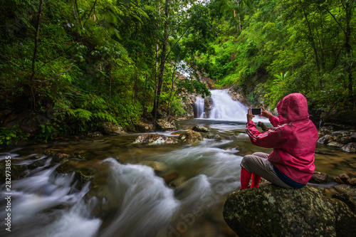 The girl in red sweater touring on Pi-tu-gro waterfall, Beautiful waterfall in Tak province, ThaiLand.