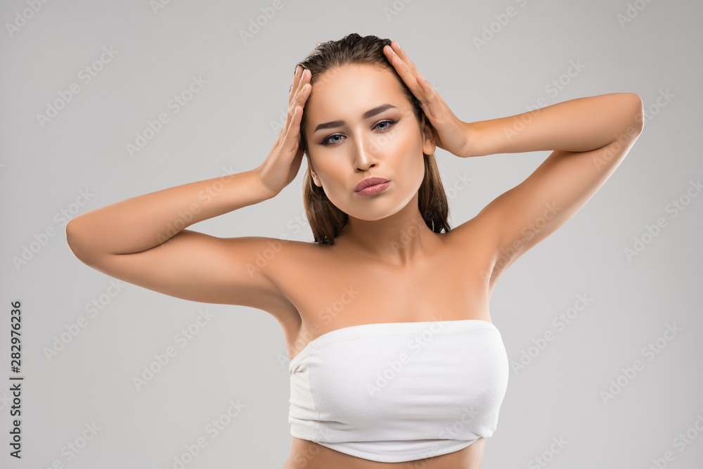 Woman holding hands behind head and looking invitingly at camera Woman holding hands behind head and looking invitingly at camera
