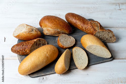 pieces different mini baguettes. Rye, wheat, multigrain bread on cutting board.