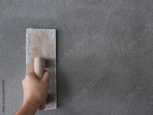 Hand of a man holds a trowel for plastering a cement wall or skimming coating on plaster walls