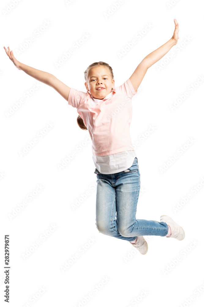 A school-age girl in a pink sweater and jeans is jumping. Vertical. Isolated over white background.