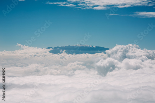 Mauna Kea summit in Hawaii. Aerial view of snow and observatories visible above clouds. photo