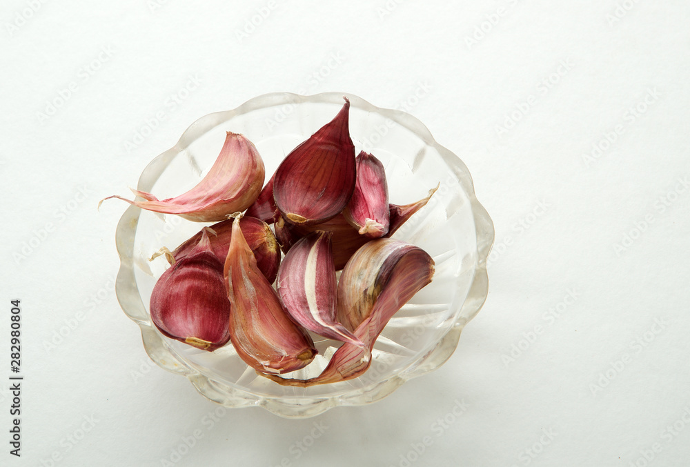 Garlic in a plate on a white background. Garlic cloves top view. Garlic in a plate on a white background. Garlic cloves top view.