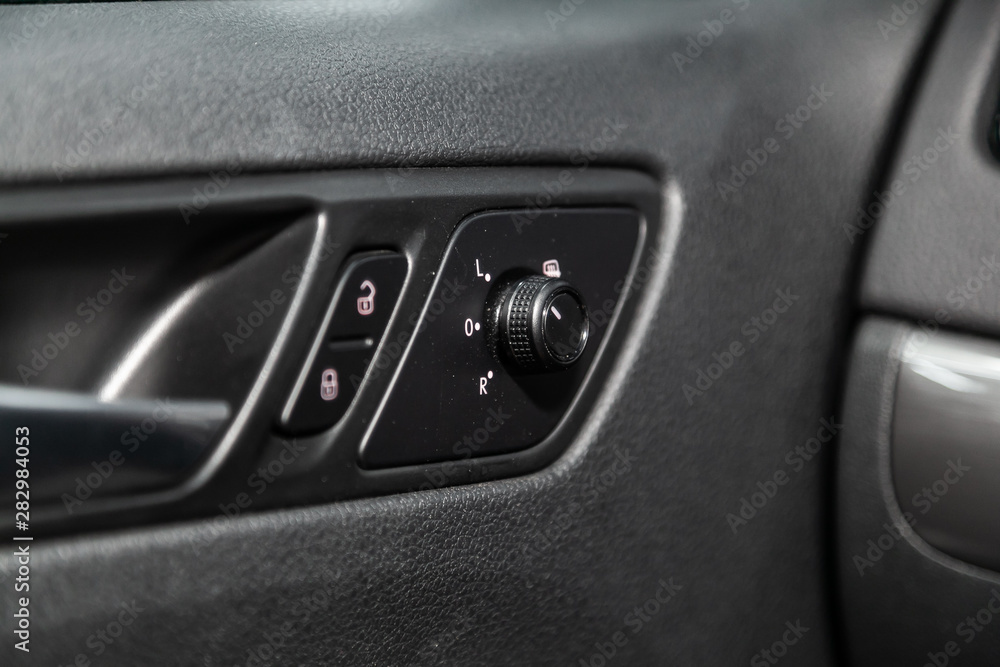 close-up of the side door buttons:  mirror, adjustment buttons, door lock. modern car interior: parts, buttons, knobs.