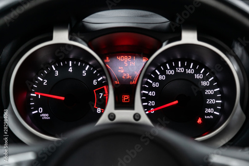 Car dashboard with white backlight: Odometer, speedometer, tachometer, fuel level, water temperature and more.