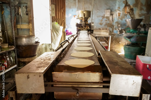 Están saliendo las tortillas de maíz de la maquina antigua.