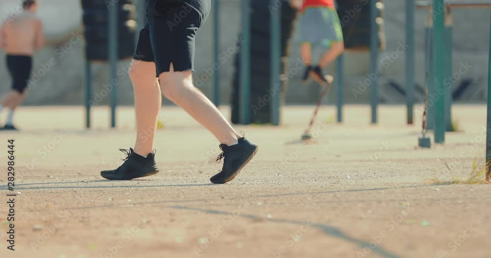 Athlete trains leg technique on a street playground. Athlete's legs are doing exercises. View from below. Athlete trains leg technique on a street playground. Athlete's legs are doing exercises. View from below.