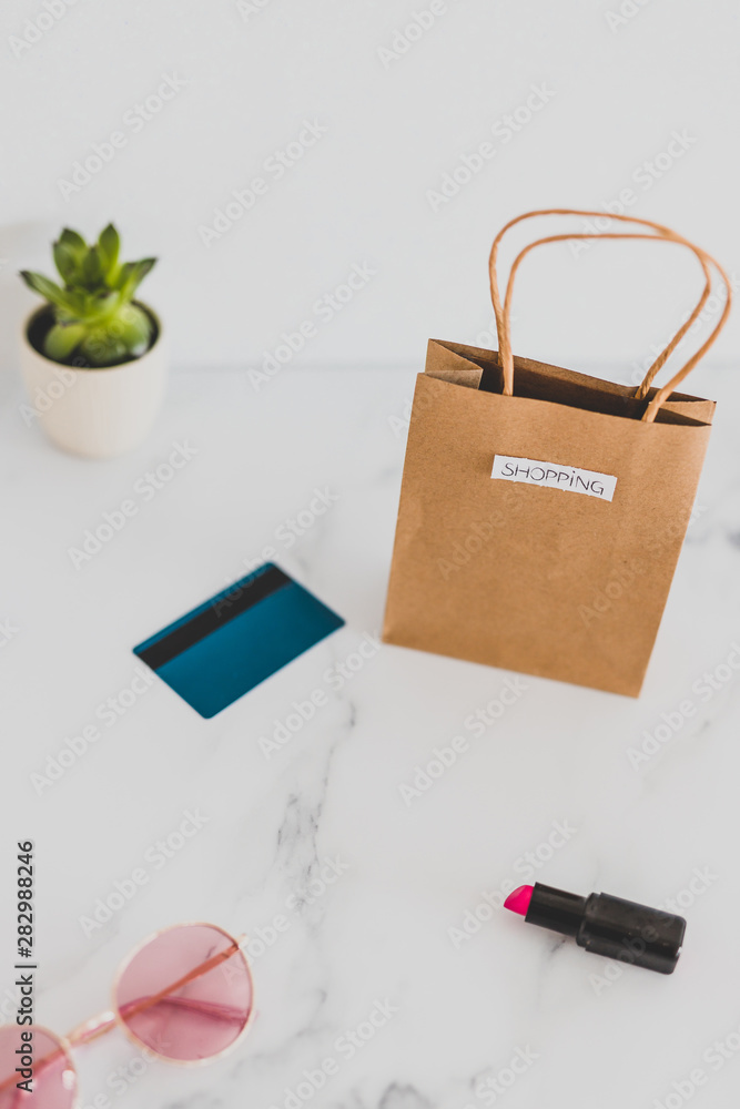 shopping bag on marble table top with mix of daily and stylish items around it and payment card shopping bag on marble table top with mix of daily and stylish items around it and payment card