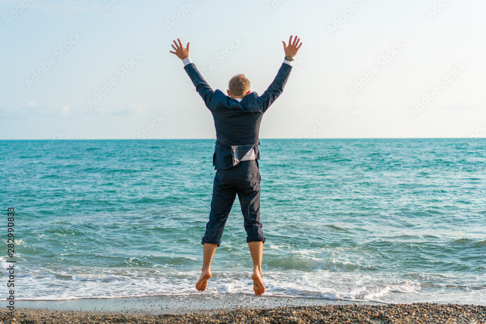 Happy businessman jumping on the beach. Man having fun by the sea. Summer vacation and travel concept Happy businessman jumping on the beach. Man having fun by the sea. Summer vacation and travel concept