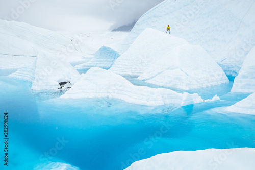 Man on a large ice fin surrounded by glacial pool on the Matanuska Glacier in Alaska