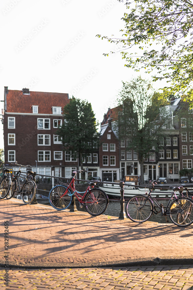 Bicycles parked along a bridge on the central streets of Amsterdam in sunset light.