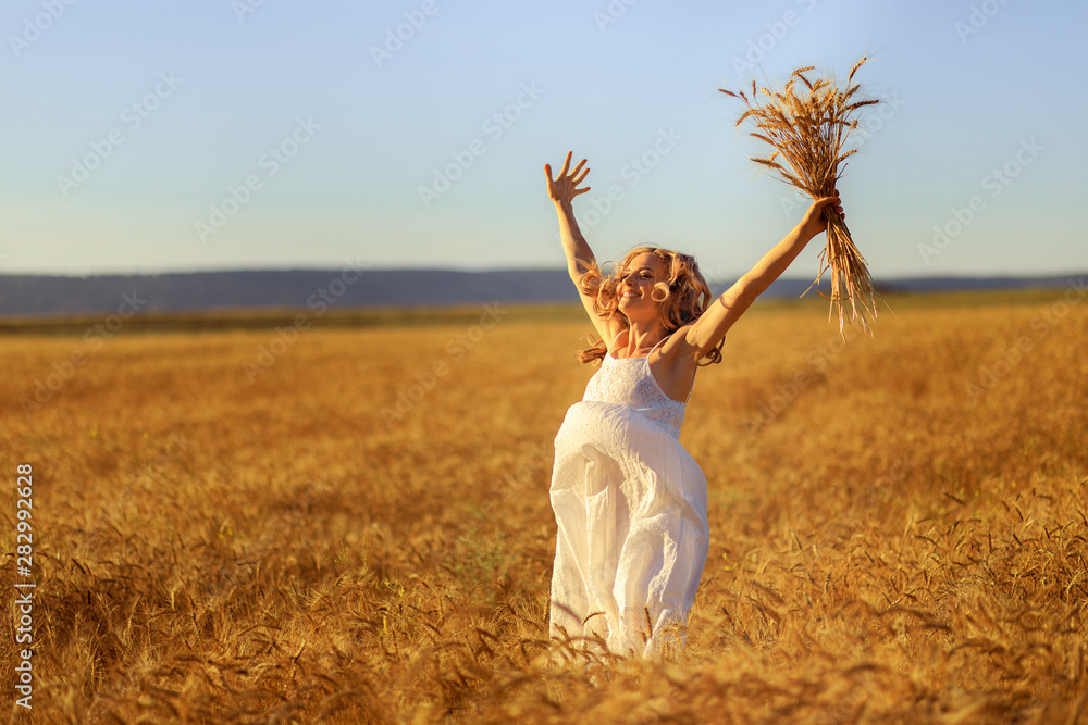 Beautiful young woman in wheat field at sunset outdoor .