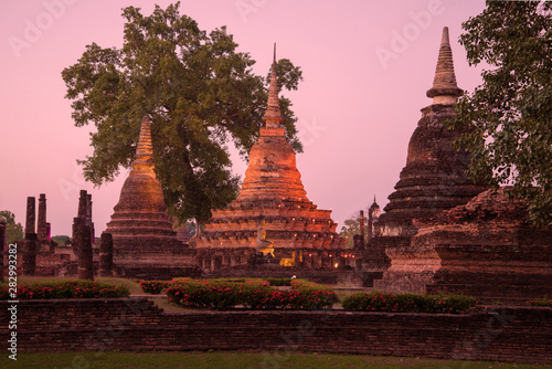 Three stupas on the ruins of the Buddhist temple Wat Mahathat at evening twilight. Sukhothai. Thailand