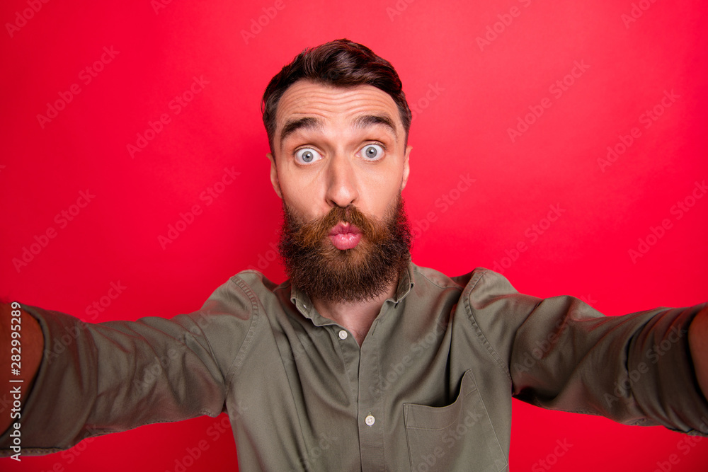 Fototapeta premium Photo of handsome man fooling in front of newly purchased camera plumping it while isolated with red background
