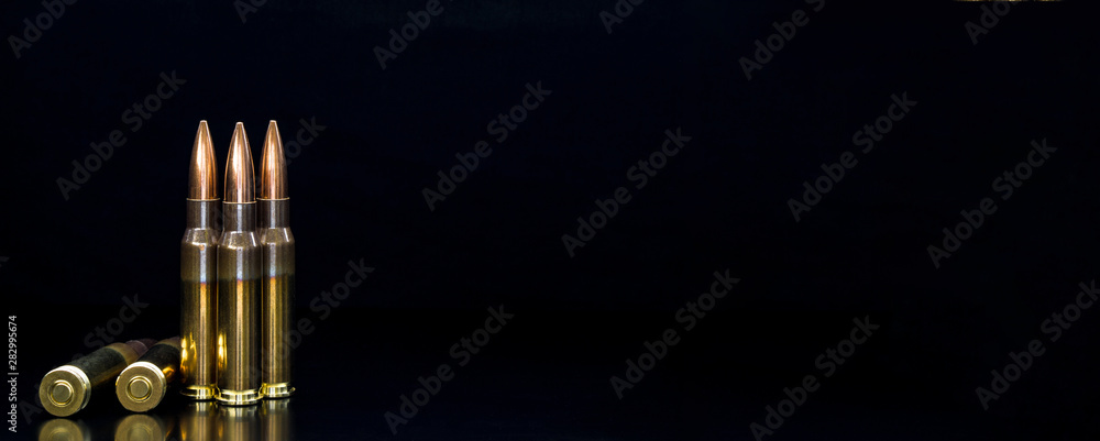 Naklejka premium Bullet isolated on black background with reflexion. Rifle bullets close-up on black back. Cartridges for rifle and carbine on a black.