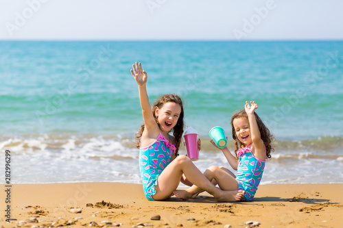 little girls sit sit opposite each other, drink from colored beautiful cocktail glasses and have fun. Family vacation