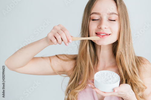 Girl holding a useful bamboo toothbrush and a jar of tooth powder