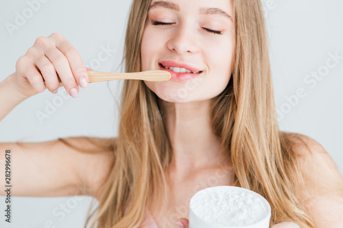 Girl holding a useful bamboo toothbrush and a jar of tooth powder