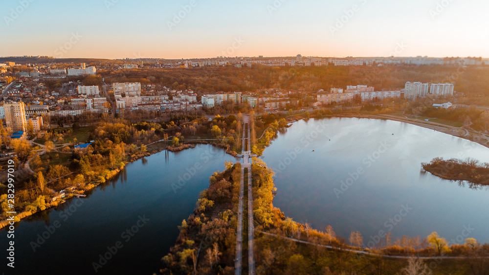 A river next to a road leading towards a city at sunrise, shot from above.