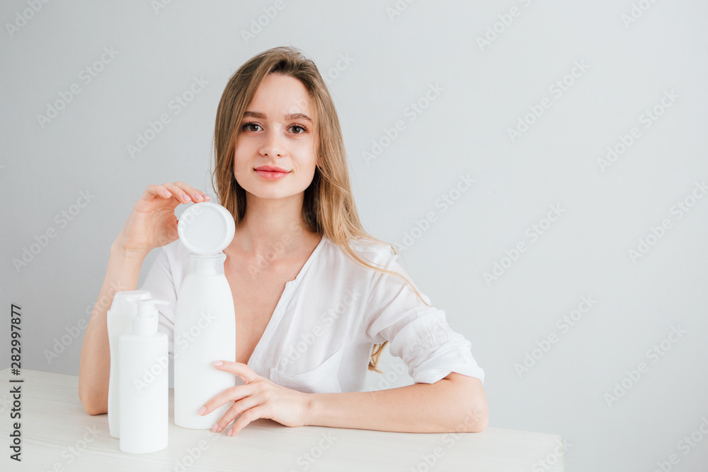 Young beautiful girl with white cosmetic bottles of different sizes Young beautiful girl with white cosmetic bottles of different sizes