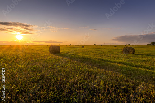 A field with haystacks on a sunset on a summer evening.