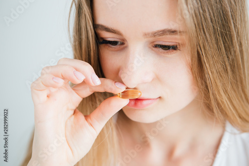 young beautiful girl puts a pill in her mouth close-up