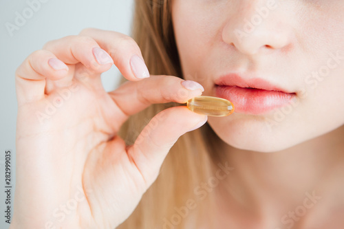 young beautiful girl puts a pill in her mouth close-up