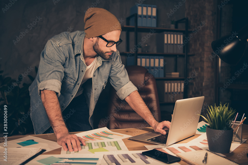 Photo of working at night time boss guy reading contract wear casual outfit stand near table in modern office Photo of working at night time boss guy reading contract wear casual outfit stand near table in modern office