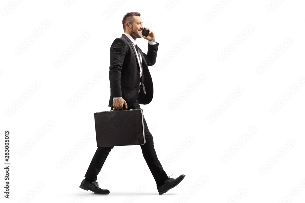 Businessman walking and talking on a mobile phone - obrazy, fototapety, plakaty 