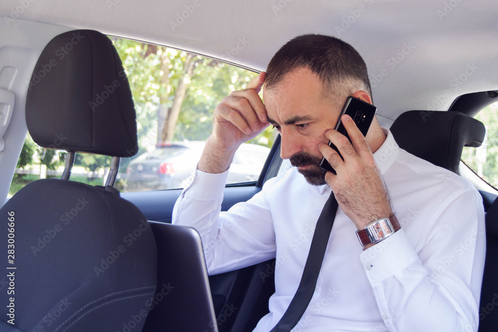 Frustrated business man / employee talking on mobile phone while sitting in the back seat of car. He has a problem and doesn't know how to solve it. Frustrated business man / employee talking on mobile phone while sitting in the back seat of car. He has a problem and doesn't know how to solve it.