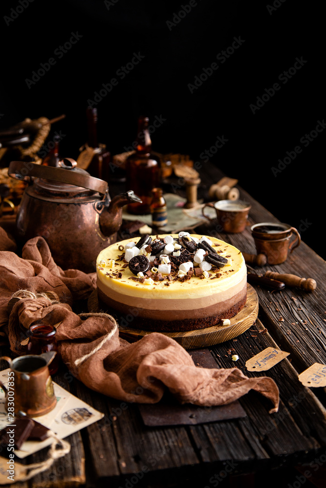 Beautiful still life with homemade delicious three chocolates cheese cake on wooden stand on rustic table