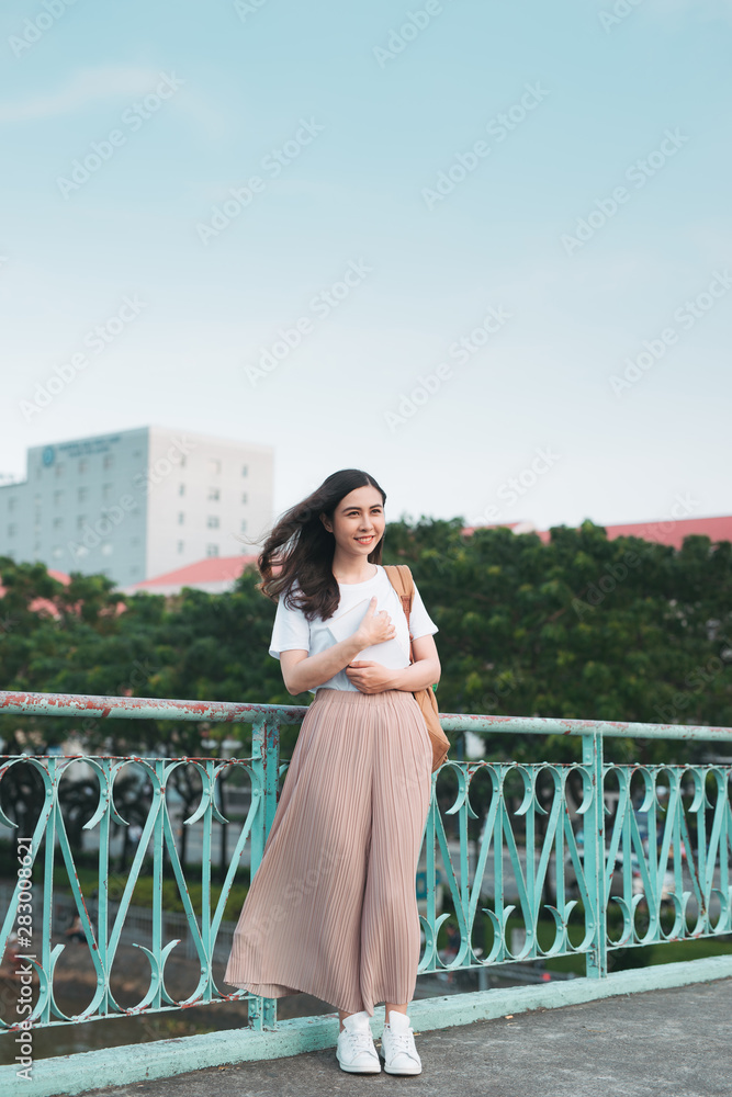 Beautiful Asian female college student holding her books standing outdoor, people education learning program college concept