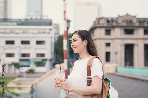 Young cute woman drinking coffee on the bridge on the city background
