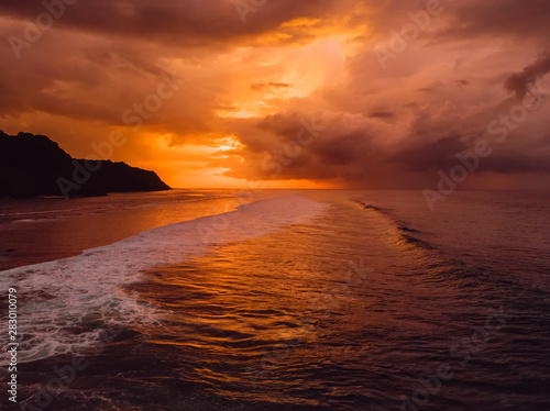 Aerial view of ocean with waves and warm sunset or sunrise.