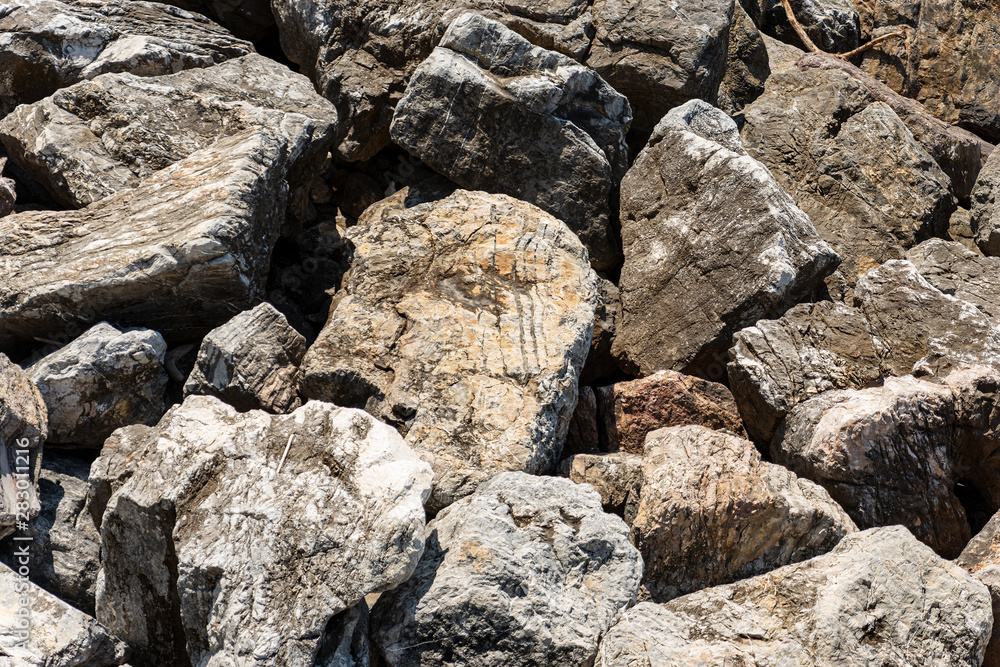 Closeup of a breakwater made of giant boulders by the sea, full frame. Liguria, Italy, Europe