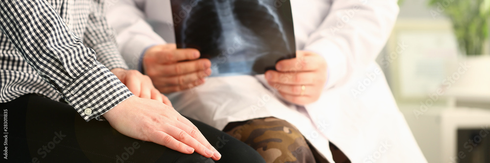 Doctor holds patient x-ray and reports bad news