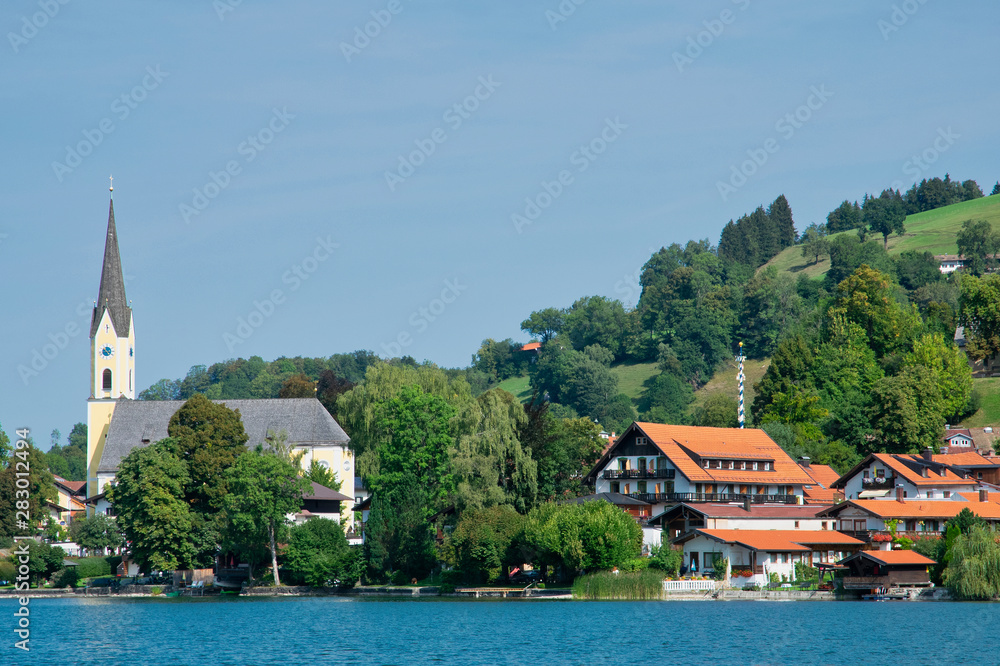 Sunny summer day on Schliersee lake with a church view and small houses in Bavarian Alps Germany  