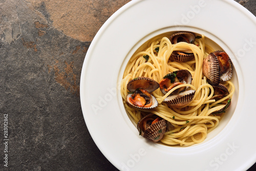 top view of delicious pasta with mollusks on weathered grey background