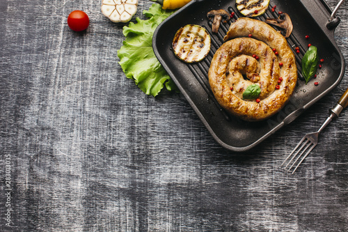 Top view of spiral grilled sausage with vegetable in pan
