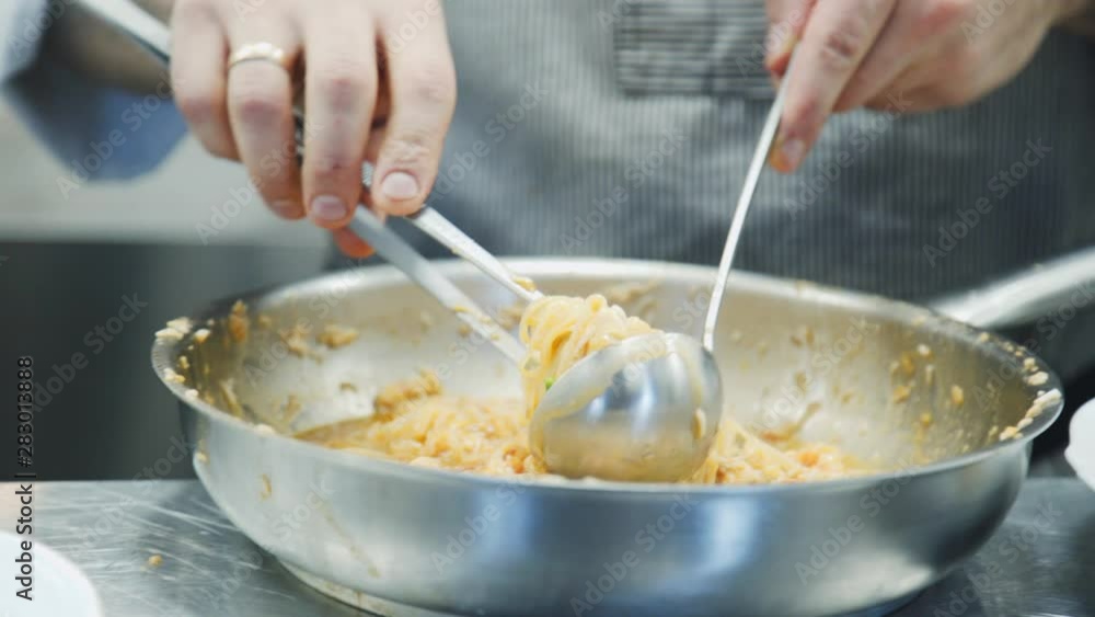 Someone making pasta in the kitchen. Chef cooking spaghetti. Food video. Pasta preparation. The pasta's in the frying pan. food video Someone making pasta in the kitchen. Chef cooking spaghetti. Food video. Pasta preparation. The pasta's in the frying pan. food video