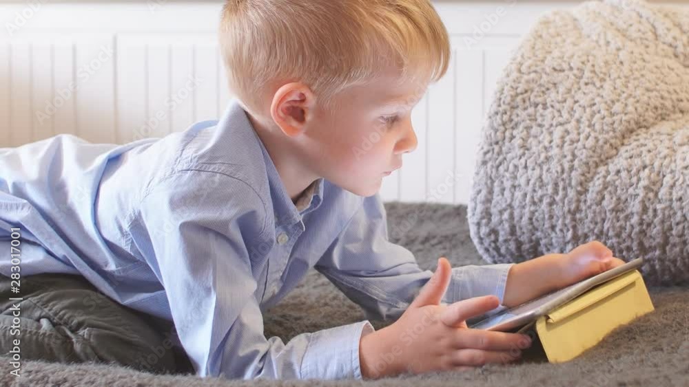 Little child uses tablet on sofa at home. Little child uses tablet on sofa at home.