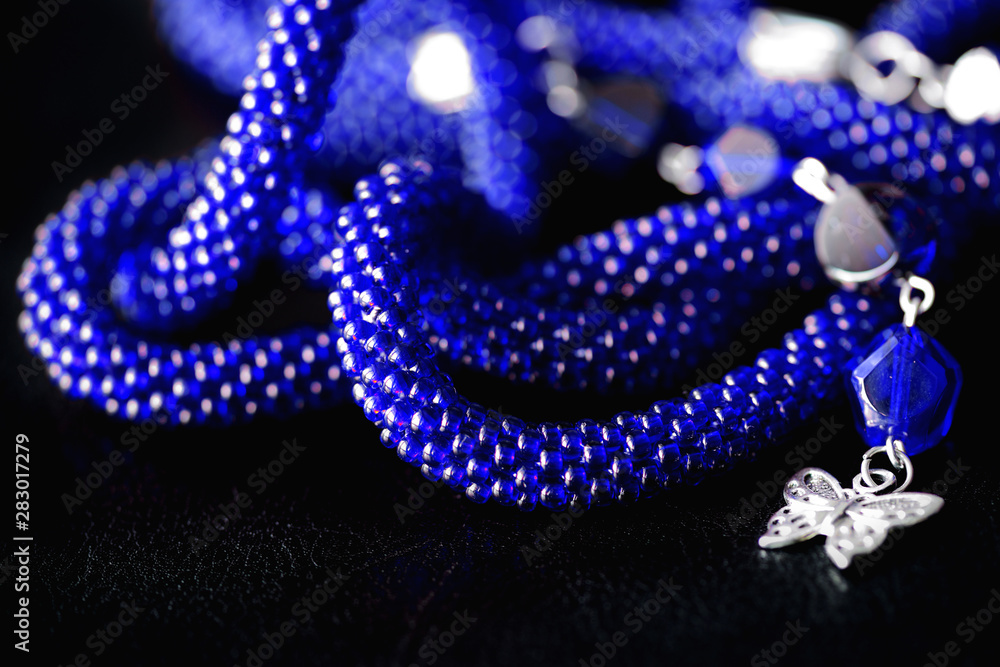 Long open necklace (lariat) blue color on a dark background close up