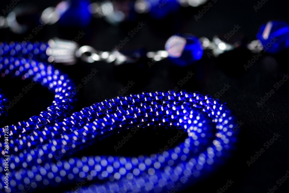 Long open necklace (lariat) blue color on a dark background close up Long open necklace (lariat) blue color on a dark background close up