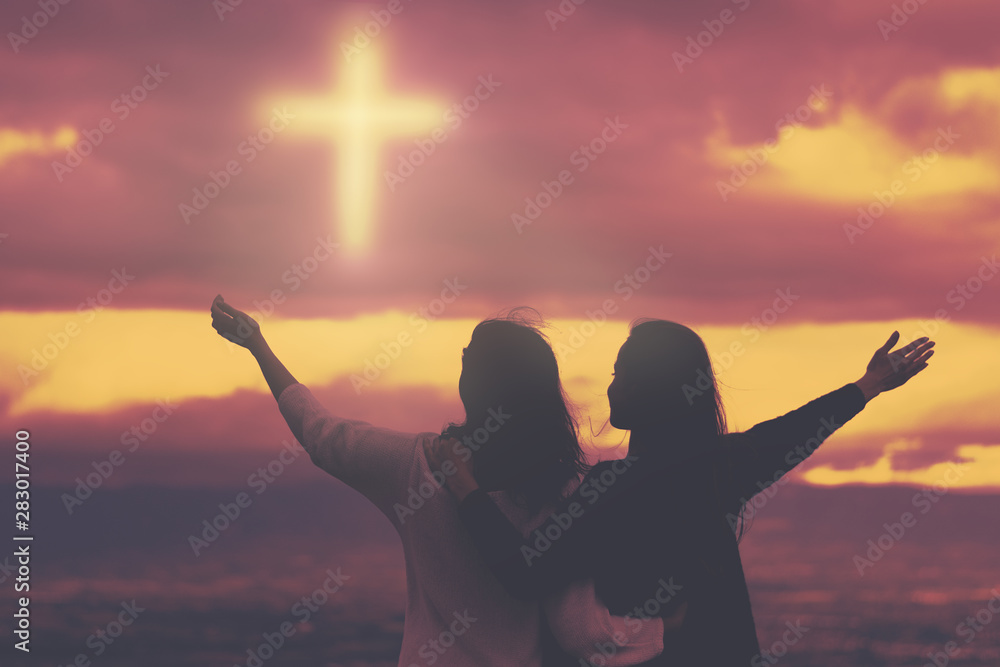 Christian worship and praise. Two young woman are praying and worshiping in the evening.
