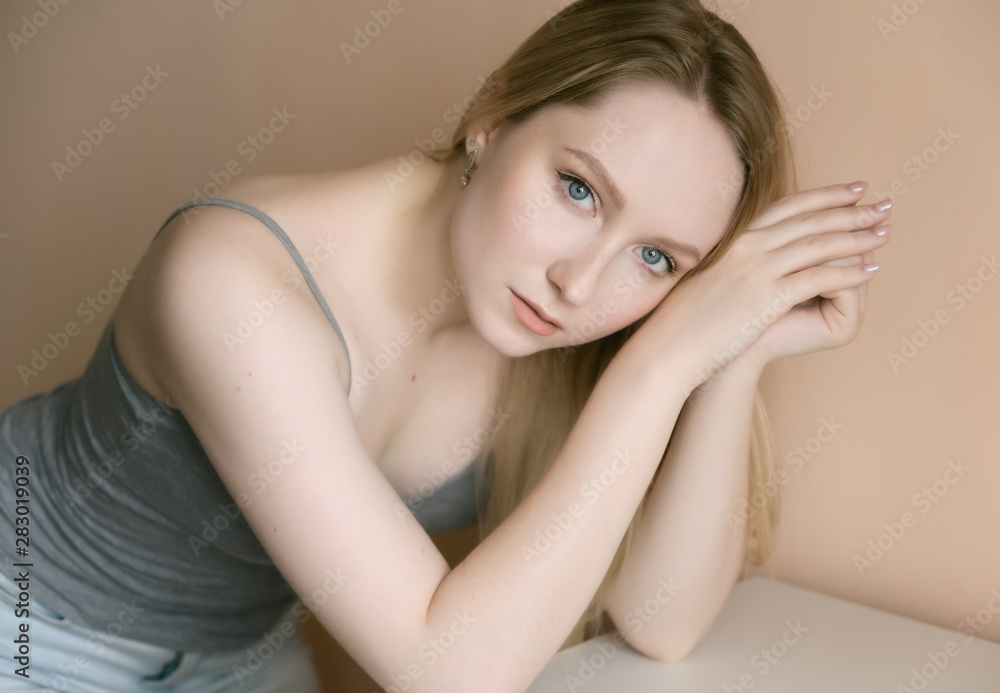 Graceful young woman posing against beige wall. Graceful young woman posing against beige wall.