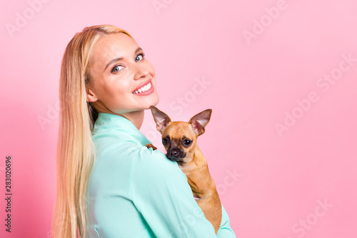 Close up photo of attractive lady hugging her pet looking with toothy smile wearing mint-colored shirt isolated over pink background