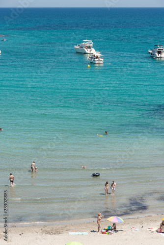 Orihuela Costa, Spain - June 16, 2018: People sunbathing and swiming at the Cala Capitan beach in the Cabo Roig, popular place for holidaymakers. Province of Alicante. Costa Blanca. Spain